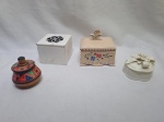 Lote composto de 4 caixas decorativas, sendo 2 em porcelana e 2 em madeira. Medindo a maior em porcelana 10cm x 7,5cm x 5cm de altura.