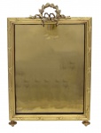 Elegante porta retrato de metal com banho de ouro, adornado por elementos decorativos dentro do padrão do estilo império, encimado por laçarote e guirlanda de alusiva ao período cafeeiro. França - Princípio do Século XX. Medida externa: 43  cm x 29 cm. Marcas de uso.