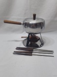 Panela de fondue com rechaud e fogareiro em aço inox, acompanha espetos com cabo em madeira. Medindo o conjunto 20cm de altura.