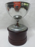 Lindo troféu tipo taça em estanho com base em madeira. Medindo 13cm x 20,5cm de altura.