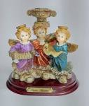 PIETRO SANTINI - Linda escultura em fina resina Italiana representando castiçal com trio de anjos tocando instrumento musical. Base madeira. medida: 15 cm de altura x 15,5 cm x 11 ,5 cm.