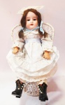 Antiga boneca com cabeça em biscuit "Daniel Kestner Dolls" Germany com cabelos castanhos longos, olhos azuis, boca aberta e corpo articulado, inclusive os punhos. roupa em tule com babados e bordados, toca e sapatos bota com pérolas. Mede 37 cm. Obs: a cadeira não faz parte desta lote.