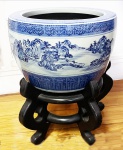 Grande cachepo em antiga porcelana chinesa de Macau, início do séc. XX , esmaltagem azul e branco com suporte em madeira nobre de 4 apoios recurvos. Cenas de paisagem campestre, bordas e base em faixas azuis desenhadas geometricamente. Acompanha marmore fino cor cinza polido com pequeno restauro na lateral, podendo ser usado como mesa lateral. Mede 34 cm de altura e diâmetro de 48 cm. Altura total c/ o suporte, 62 cm. O mármore tem 47 cm de diÂmetro.