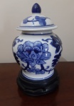 Potiche em porcelana azul e branco com tampa. Acompanha base original de madeira trabalhada - Altura: 18 cm (incluindo base) e Diâmetro: 7,5 cm (base)