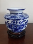 Mini vaso em porcelana branca com desenho na cor azul. Acompanha base original de madeira trabalhada - Altura: 12 cm e Diâmetro: 6 cm (base)