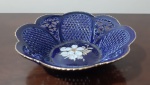 Encantadora cesta decorativa em porcelana húngara feita e pintada à mão com decoração floral central, laterais vazadas, na cor azul com detalhe ouro na borda. Diâmetro: 11 cm e Altura: 3 cm