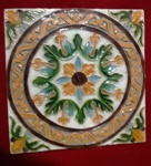 Antiga e bonita peça em cerâmica   (azulejo), medindo 25,5x25,5 cm., vidrado em relevo, com desenhos de flores, diversas cores, predominando amarelo e verde, marca estampada no verso, espessura de 1 cm., muito bom estado.