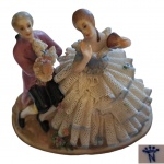 Escultório em porcelana CapodiMonte representando casal da corte em cena galante, ela com vestimenta rendada petrificada, marcado na base, apresenta grande falha renda parte posterior, 11 x 7, Alt. 9 cm.