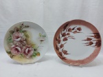 Lote de 2 pratos decorativos em porcelana pintada à mão. Medindo o maior 27,5cm de diâmetro.