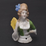 Coleção Half Doll - Dama com vestimenta verde, cabelos de época e leque amarelo nas mãos. Base numerada e marcada Germany. Mede 8x5 cm.