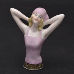 Coleção Half Doll - Jovem dama com lenço rosa na cabeça e lindos cachos. Sua expressão é rara e delicada, esta com as duas mãos atras do pescoço. Base marcada e numerada. Med 7,5 x 6 cm.