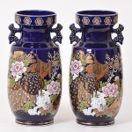 Par de vasos em porcelana oriental, tonalidade azul cobalto com detalhes em ouro, ao centro representação de pavões e peônias. (Alt.: 30cm / Diam.: 11cm)