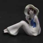 Coleção Half Doll -  Lady sunbathing. Rara representação de dama de corpo inteiro. Vestimenta em tons de azul e verde. Grande sombreiro aonde ela apoia sua mão. Med 6 x 8 cm.