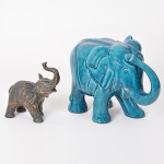 Lote composto por 1 escultura de Elefante em metal fundido e cinzelado e 1 escultura de Elefante em porcelana esmaltada em tons de azul (ausência de 1 presa) . - Total 2 peças - Obs.: No estado. (18x7x18 / 24x17x34)