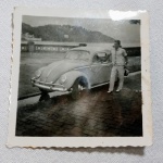 Foto em preto e branco de um Volkswagen Fusca clássico estacionado em uma rua de paralelepípedos. Ao lado do carro, há um homem. Ao fundo o mar. Aprox. 5 x 5 cm. Detalhes conforme fotos, _(ºLº)_ Caso necessite, tire todas suas dúvidas via atendimento personalizado por WhatsApp: (11) 98681-9377 ou pelo e-mail: contato@antiguera.com.br, onde você pode solicitar fotos detalhadas. Não deixe para última hora! Antecipadamente agradecemos pelo seu lance. Sem garantias futuras