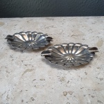 Antigo par de cinzeiros de mesa em metal prateado trabalhado. 13 X 7 cm. Detalhes conforme fotos, _(ºLº)_ Caso necessite, tire todas suas dúvidas via atendimento personalizado por WhatsApp: (11) 98681-9377 ou pelo e-mail: contato@antiguera.com.br, onde você pode solicitar fotos detalhadas. Não deixe para última hora! Antecipadamente agradecemos pelo seu lance. Sem garantias futuras ou de procedência.