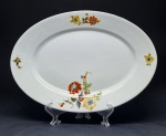 Porzellanfabrik Tielsch & Co., Alemanha (atualmente parte da Polônia), 1934. Elegante e nonagenária travessa em porcelana branca decorada com motivos florais e detalhes em dourado. Medidas = 38 x 26 cm. Em bom estado de conservação.