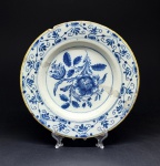 Prato em porcelana chinesa de exportação para o Ocidente, com decoração floral no tom azul na caldeira. Diâmetro = 22,5 cm. Marcas de restauro antigo e um considerável bicado na borda, visível dos dois lados.