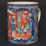 <b>Caneca cilíndrica </b>em porcelana Companhia das Índias decorada com grande reserva com personagens em cena do cotidiano. Restante do bojo com flores e arabescos em azul índigo e "rouge de fer" realçado a ouro. Séc. XVIII. Alt. 12 cm