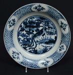 <b>Covilhete</b> fundo circular em porcelana chinesa, decorado em azul índigo "underglaze" com figura de fênix entre ramagens. Séc. XVIII ou início do séc. XIX. Diâm. 28 cm