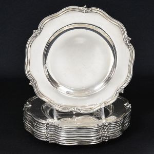 <b>Conjunto de 10 pratos para sobremesa</b>, em prata portuguesa, feitio liso, com borda em ondulações intercaladas por pequenas volutas. Contraste da cidade de Lisboa usado de 1886 a 1938 e marca de prateiro. Peso  2.265 g. Diâm. 21,5 cm