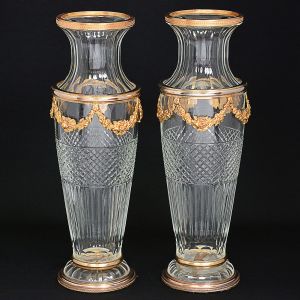 <b>MAISON BACCARAT - Belíssimo par de grandes vasos </b>em cristal translucido multi lapidado com montagem em bronze ormolu modelado em guirlandas. Borda e base decorados com pequenos arabescos. Marca da "cristallerie". Séc. XIX. Alt. 50 cm