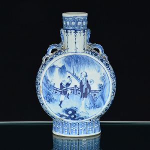 <b>"Moon flask" </b>em porcelana Companhia das Índias, decorado em azul índigo sobre fundo branco. Ambas as faces apresentam figuras em cena de terraço. Restante da peça com arabescos floridos. Alças modeladas em quimeras. Ideogramas no verso. Início do séc. XIX. Alt. 30,5 cm