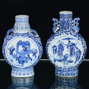 <b>Conjunto de 2 "moon flasks" </b>em porcelana Companhia das Índias, Jiaqing, decorados em azul índigo "underglaze" sobre fundo branco. Um deles decorado com cena festiva e alças modeladas em quimeras. O outro com personagens em cena do cotidiano e alças vazadas. Alt. 21 e 22 cm