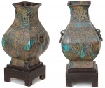 Belíssimo <b>par de vasos </b>arcaicos em bronze chinês lavrado e policromado com parte inferior bojuda e gargalo quadrangular levemente aberto. Pegas laterais com argolas. Pertenceu à importante coleção Regina Ferraz. Datado provavelmente da Dinastia Han. Acompanham bases em madeira. Fundo com orifício central já tendo sido usado como "abatjour". Alt. 36 cm; Larg. 20 cm