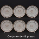 <b>Conjunto de 42 pratos</b>, sendo 18 fundos e 24 rasos, em porcelana Companhia das Índias, apresentando fundo monogramado inserido em reserva ovoide com estilizações a ouro. Borda em policromia com arabescos floridos decorados por pequenos botões de flores e semicírculos. Período Jiaqing. Diâm. 25 cm