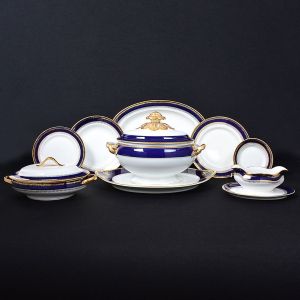 <b>Serviço de jantar em porcelana</b> portuguesa Vista Alegre, com fundo branco e bordas decoradas em azul cobalto e ouro. Marca da manufatura no verso. Constando de 19 pratos rasos, 12 pratos fundos, 9 pratos de sobremesa, 11 pratos de pão, 1 terrina c/ "presentoir", 1 legumeira c/ tampa, 5 travessas de vários tamanhos e 1 molheira. Total de 59 peças. Med. da travessa maior 38 cm; Med. da travessa menor 27 cm