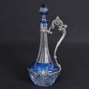 <b>"Claret jug" </b>em cristal europeu de gargalo alongado, incolor e azul, lapidado em elementos geometrizados e serrilhados. Montagem em prata portuguesa com estilizações vegetais e friso retorcido. Contraste da cidade do Porto usado de 1886 a 1938. Alt. 37,5 cm