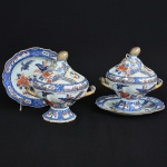 <b>Par de terrinas para molho com seus respectivos "presentoirs"</b> em porcelana japonesa "Imari", decoradas em suas tonalidades características com pegas das tampas em forma de frutos e realces a ouro. Séc. XIX. Compr. da sopeira 19 cm; Compr. do "presentoir" 20 cm