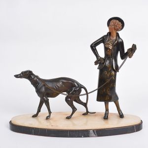 <b>Escultura</b> em bronze com o rosto em resina representando elegante dama com galgo. Base oval em mármore. Alt. 33 cm; Compr. 40 cm