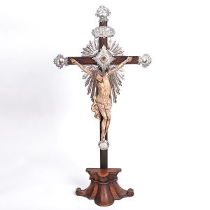 Belíssimo <b>crucifixo</b> brasileiro em jacarandá com a imagem do crucificado em madeira patinada, belamente entalhada. Ponteiras e adereços em prata ricamente lavrada. Séc. XVIII. Alt. 85 cm