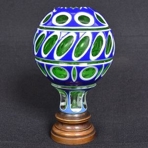 <b>Pinha</b> globular francesa em cristal na cor verde esmeralda com "overlay" em azul cobalto e branco. Lapidação com geometrizados e topo com elemento estrelado. Base em bronze. Séc. XIX. Séc. XIX. Alt. 15 cm