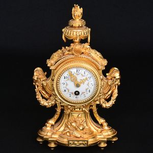 Belo<b> relógio francês Louis XVI</b> com mostrador circular em placa de porcelana esmaltada com guirlandas e rica montagem em bronze ormolu. Decoração com alegorias e cabeças de carneiro sustentando guirlandas. Ao topo urna com lábaro. Pedestal recortado e pés em ponteiras. Séc. XIX. A placa com mínimo defeito na parte superior. Alt. 23 cm; Larg. 14 cm