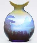 <b>EMILE GALLÉ - Rio de Janeiro - Vaso</b> globular com bocal de forma navicular em "cameo glass" de tonalidade levemente amarelada e diversas nuances de azul. Em uma das faces o Morro do Corcovado tomado da enseada de Botafogo com seu casario e do outro, o Morro da Urca e o Pão de Açúcar. Exuberantes palmeiras e bananeiras nas laterais e outros vegetais completam o conjunto. Assinado. Este lote foi cedido para a exposição "Guanabara, o Abraço do Mar", na FGV Rio, em cartaz até 27 de fevereiro de 2025, e poderá ser retirado logo após o término da exibição. Alt. 22,5 cm