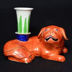 <b>Castiçal</b> em porcelana Companhia das Índias, modelado em cão de fó, em "rouge de fer" realçado a ouro. Receptáculo em verde e azul cobalto decorado com folhas. Séc. XVIII / XIX. Alt. 12 cm; Compr. 17 cm