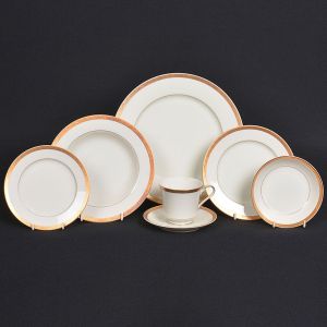 <b>Conjunto de jantar e chá </b>em porcelana japonesa na cor creme com barra de arabescos a ouro. Constando de 8 pratos rasos, 8 pratos para sobremesa, 6 pratos para sopa, 7 pratos para pão, 11 covilhetes, 1 travessa oval, 2 "bowls" redondo, 5 xícaras de chá com pires, 1 molheira com base, 1 leiteira e 1 açucareiro. Marca da manufatura no verso. Total de 51 peças.