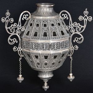 <b>Lampadário</b> em prata portuguesa com bojo vazado e profusamente decorado com composições floridas centralizando seção com figuras emplumadas dispostas lado a lado, delimitadas por colunas. Três hastes de sustentação em elaborados recortes terminados em trevos com ponteiras pendentes. Contraste da cidade do Porto usado de 1861 a 1870 e marca do prateiro JFC. Peso 3000 g. Alt. 48 cm