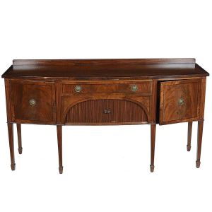 <b>"Sideboard" inglês</b> vitoriano construído em mogno. Caixa retangular levemente abaulada à frente apresentando duas portas laterais centralizando gavetão e armário com portas em esteirinha. Pernas retilíneas levemente afiladas e frisos em baixo relevo. Ferragens de época modeladas em rosetas e perolados. Séc. XIX. Med. 92 x 184 x 63 cm