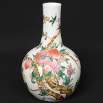 <b>Vaso </b>bojudo de gargalo alongado, em porcelana chinesa, decorado em policromia com figuras de pêssegos entre ramagens floridas. Alt. 33,5 cm