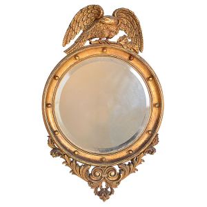 Antigo <b>espelho</b> circular bisotê, europeu, no estilo "Regency". Apresenta moldura em madeira entalhada e dourada encimada por figura de águia e parte inferior com volutas. Provavelmente séc. XIX. Med. 88 x 55 cm