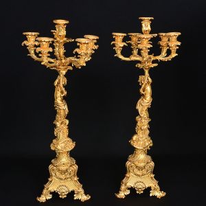 Grandioso <b>par de candelabros</b> franceses do séc. XIX, para seis luzes cada. Braços recurvados, recamados por volutas e implantados em cornucópias sustentadas por "puttis" sentados sobre colunas, essas modeladas em "coquilles" e guirlandas em espiral. Bases trípodes decoradas com os elementos já descritos e motivos barrocos. Peças já preparadas para serem eletrificadas. Alt. 79,5 cm