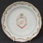 Aristocracia luso brasileira  <b>Covilhete</b> circular em porcelana Companhia das Índias decorada em policromia florida com guirlandas e reserva monogramada encimada por laço. Borda em suave ondulação, com mínimo fio e pequenos riscados no fundo. Séc. XVIII. Diâm. 14 cm