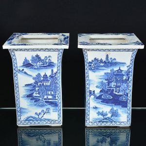 <b>Par de jardineiras </b>em porcelana chinesa, apresentando forma quadrangular e decoração com paisagens lacustres e pagodes em azul índigo "underglaze". Med. 40 x 28,5 x 28,5 cm