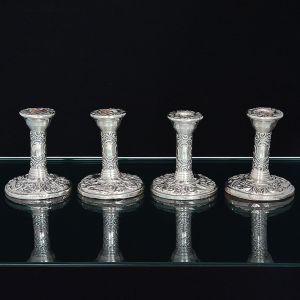 <b>Conjunto de 4 pequenos castiçais </b>em prata portuguesa. Haste cilíndrica e base circular decoradas em profuso lavrado de motivos vegetais e pássaro. Contraste da cidade de Birmingham de 1961 e marca do prateiro B&Cº. Apresentam enchimento. Alt. 10 cm