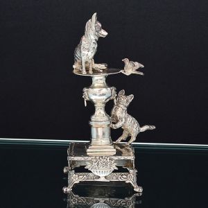 Belo <b>paliteiro</b> em prata 833 ml, modelado em taça bebedouro com cão e pássaro sobre ela e figura de gato apoiado sobre base quadrada. Pés em garras. Contraste parcialmente ilegível da cidade do Porto. Peso 350 g. Alt. 16 cm