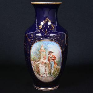 Belo <b>vaso</b> em forma de balaústre, em porcelana francesa de Limoges, coberto por esmalte azul cobalto realçado a ouro. Na face anterior grande reserva decorada por cena romântica em policromia com assinatura Angeli. No verso marca da manufatura M. Fres - Limoges. Séc. XIX. Alt. 35 cm